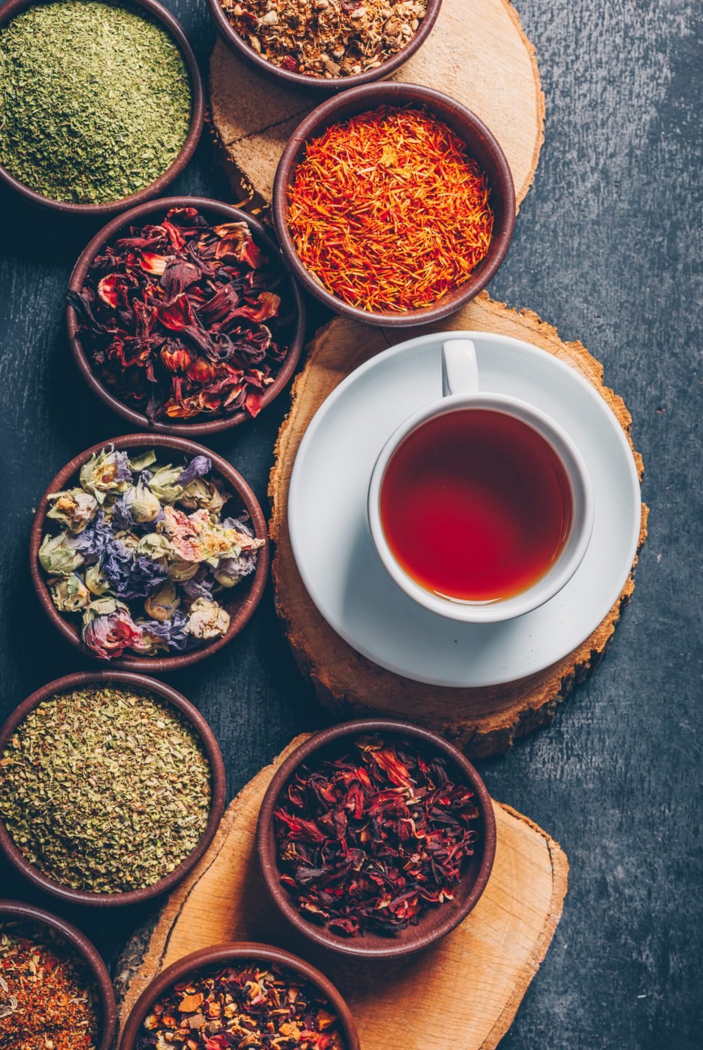 Set of wood stubs and a cup of tea and tea herbs in a bowls on a dark textured background. flat lay. Set of wood stubs and a cup of tea and tea herbs in a bowls on a dark textured background. flat lay.